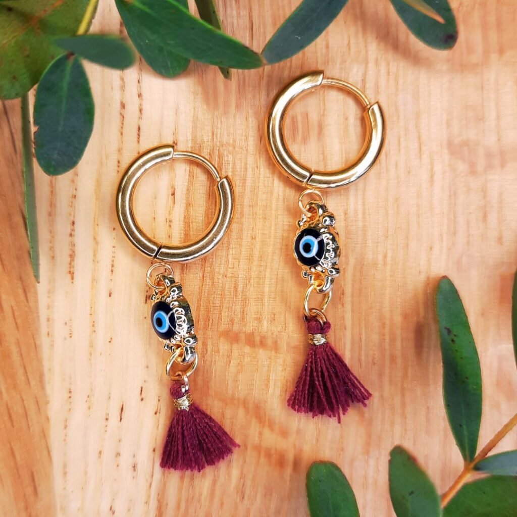 Sensational mauve evil eye tassel hoops